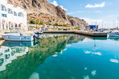 Sailboats moored at harbor by sea against sky