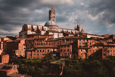 Buildings in town against cloudy sky