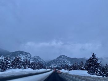 Road by snowcapped mountains against sky during winter