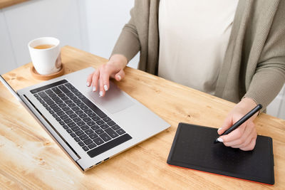 Midsection of man using laptop on table