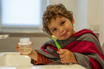 Portrait of boy drinking water from glass on table