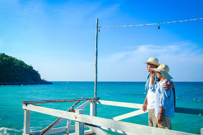 Couple wearing hat standing against sea