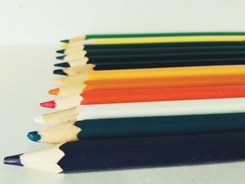 Close-up of colored pencils on arranged on white table