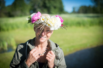 Portrait of smiling woman wearing flowers by field