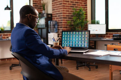 Side view of man using laptop at office