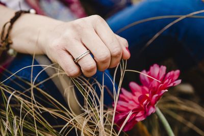 Close-up of woman hand with ring over red flower