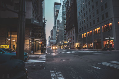 Illuminated city street amidst buildings at night