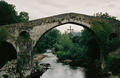 Arch bridge over river against sky