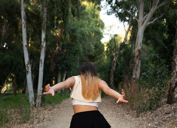 Rear view of woman standing amidst trees in forest