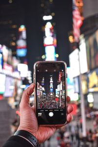 Close-up of hand holding smart phone on city street