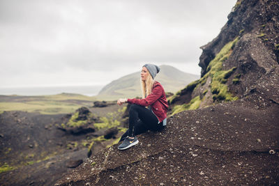 Woman sitting on rock against mountain
