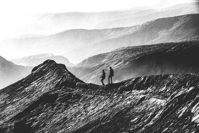 People on mountain range against sky