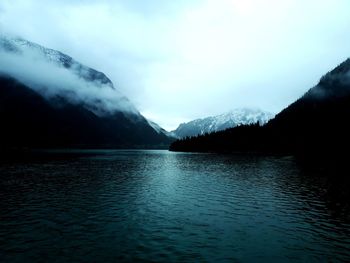 Scenic view of lake by mountains against sky