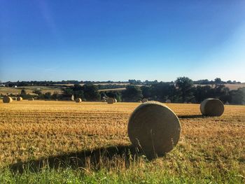 Hay bales on field against clear sky