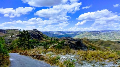 Scenic view of road by mountains against sky