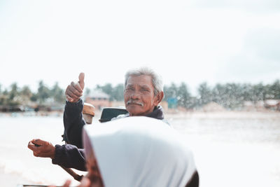 Portrait of man with arms raised against sky