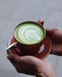 Close-up of hand holding matcha latte