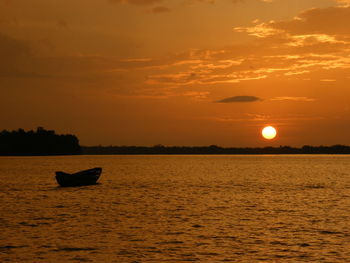 Silhouette boat in sea against sky during sunset