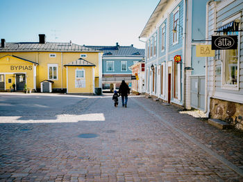 Rear view of man walking on street amidst buildings in city