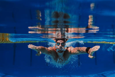 Professional male swimmer practicing underwater swimming in pool