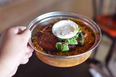 Close-up of hand holding food in bowl at home