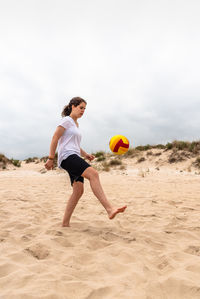 Full length of girl playing with ball on beach