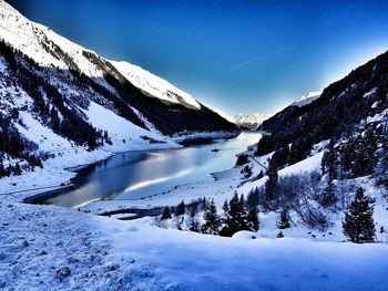 Scenic view of snow covered mountains against blue sky