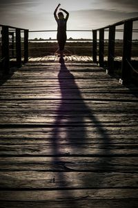 Low section of woman standing on pier at footbridge