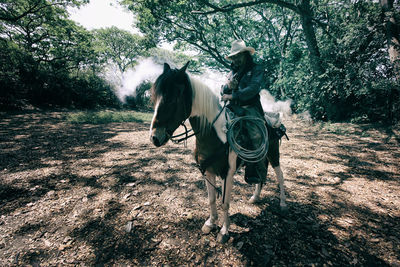 Two people riding horse on field