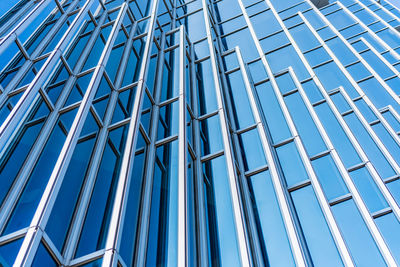 Low angle view of glass building against blue sky