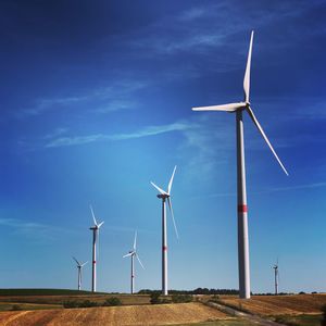 Low angle view of wind turbines on field against sky