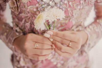Close-up of hand holding pink flower
