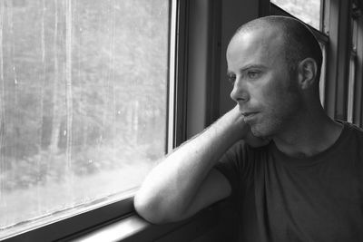 Thoughtful man looking through window while traveling in train