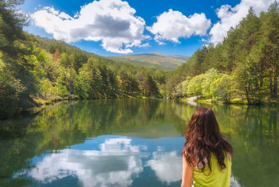 Rear view of woman looking at lake against mountain