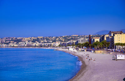 Scenic view of sea and buildings against clear blue sky