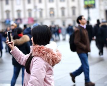 Side view of woman taking selfie in city