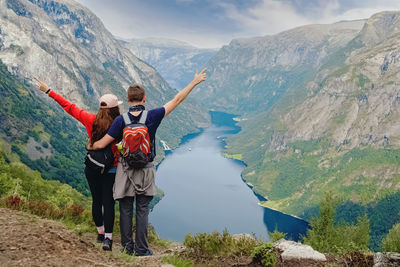 Couple of hikers standing on top of the mountain with their hands raised. traveling in norway fjords