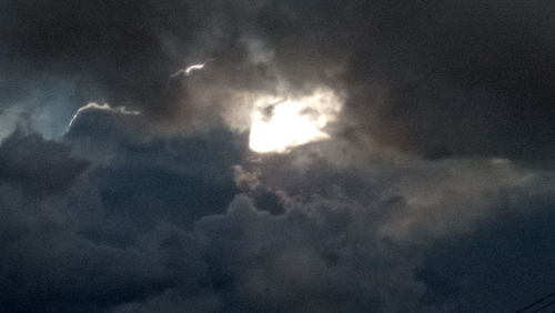 Low angle view of sun shining through clouds