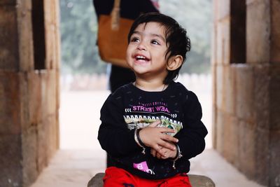 Smiling girl looking away while sitting in corridor