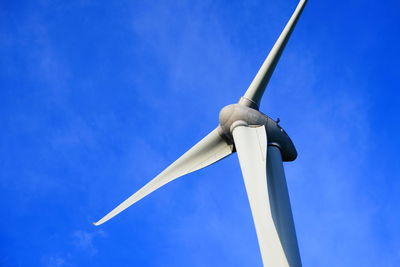 Low angle view of wind turbine against blue sky