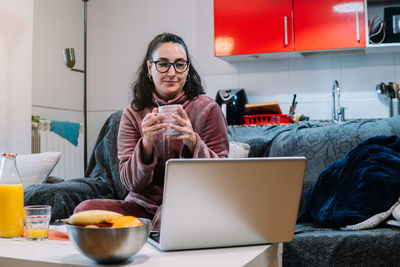 Portrait of woman using laptop while sitting at home
