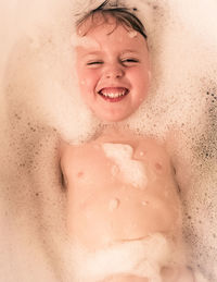 Portrait of boy lying in bathtub