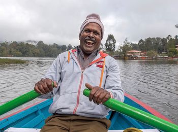 Portrait of a smiling young man holding boat in river