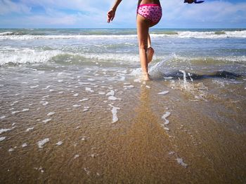 Low section of playful girl on shore at beach