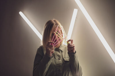 Woman holding colorful equipment against illuminated light