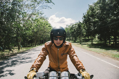 Man riding bicycle on road against trees