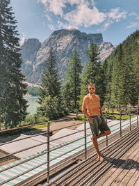 Full length of shirtless man standing on mountain against sky