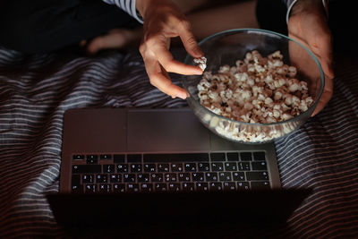 Woman in a striped sweatshirt and hat eats popcorn and watches a movie on tv or a tv series at