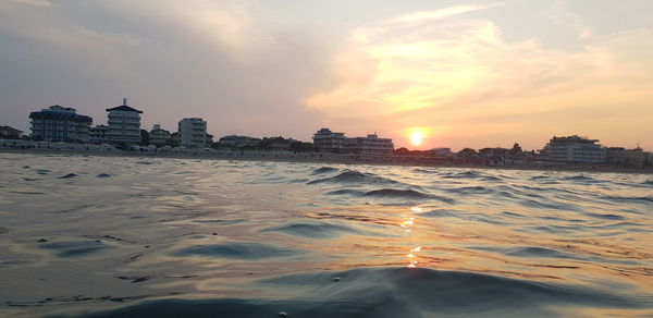 Scenic view of sea and buildings against sky during sunset