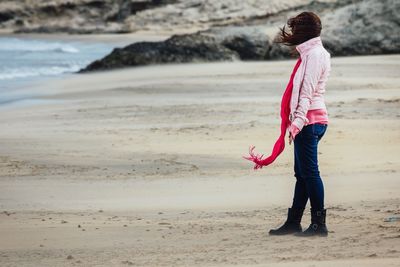 Side view of woman standing on beach against sky